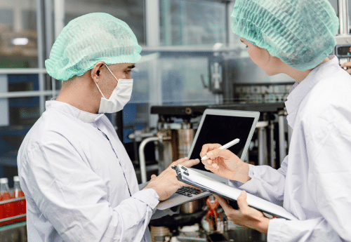 Contrôle qualité dans l’agroalimentaire – techniciens agricoles vérifiant la conformité aux normes sanitaires sur une chaîne de production, à l’aide d’outils numériques.