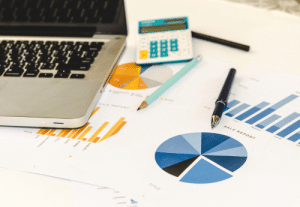 Documents de reporting avec graphiques, ordinateur portable et calculatrice – analyse des objectifs financiers et tableaux de bord pour la gestion d’une exploitation agricole.