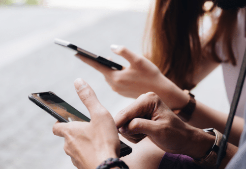 Cheffe d'entreprise et son collaborateur utilisant leurs smartphones pour naviguer sur les réseaux sociaux – stratégie digitale et communication locale pour commerçants et artisans via Instagram, Facebook et TikTok.

