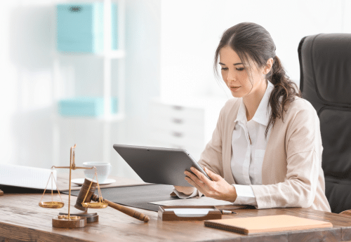 Professionnelle du droit consultant une tablette dans son bureau, illustrant l’usage d’un logiciel de gestion pour avocat ou notaire, avec le soutien d’un cabinet d’expertise comptable spécialisé.

