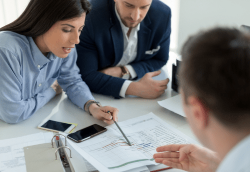 Réunion entre professionnels analysant des documents et graphiques financiers, illustrant l’interopérabilité des logiciels juridiques et la coordination entre juristes, avocats et experts-comptables.

