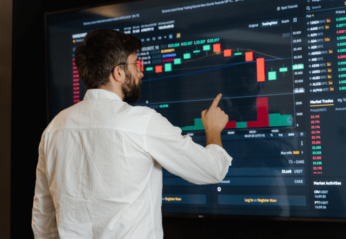 Homme en chemise blanche analysant un graphique de performance financière sur un grand écran, illustrant le rôle des données comptables dans le pilotage de la conformité, la sécurisation des processus internes et la prévention des risques en cas de contrôle fiscal ou social.

