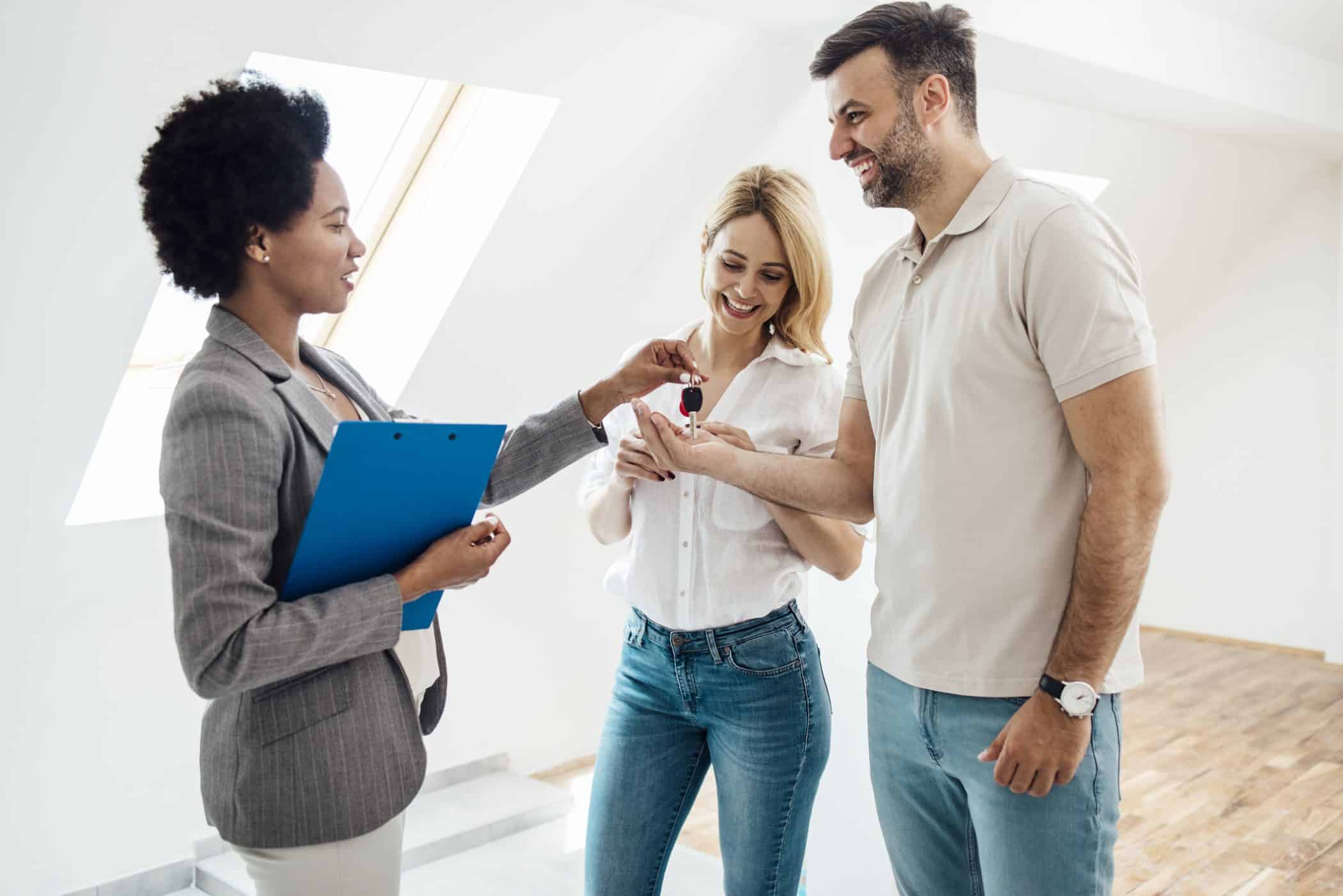 Une agent immobilière donne les clés à des clients pour l'achat de leur maison. 