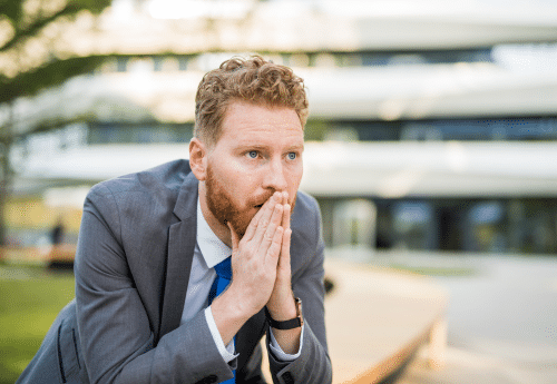 Un homme bien habillé, assis dehors, qui réfléchit et anticipe.